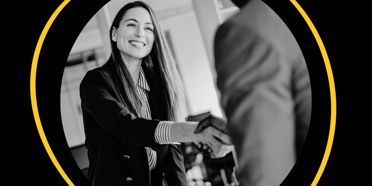 Smiling business woman shakes hands with a man in suit