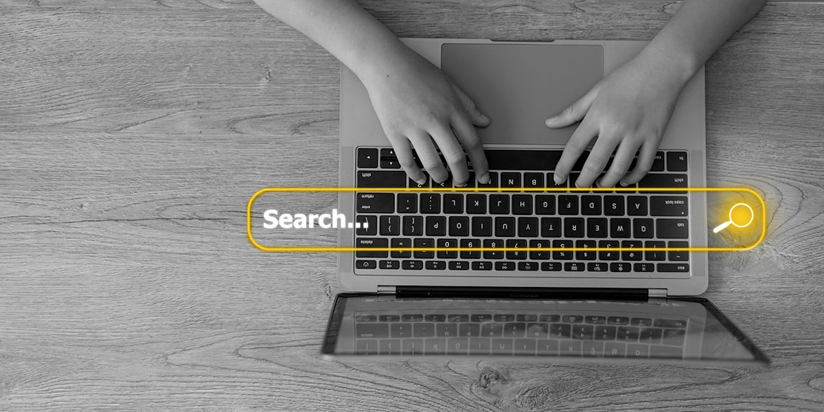 Someone typing a search query into a search engine on a laptop