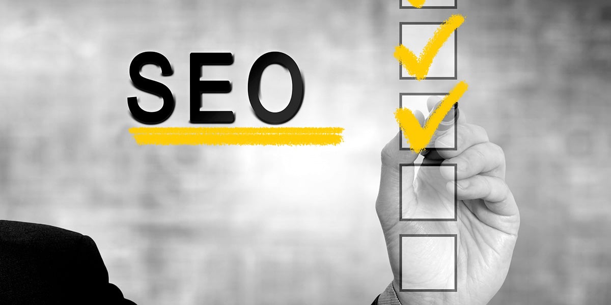 A hand holding a yellow pen marks off boxes in a basic SEO checklist