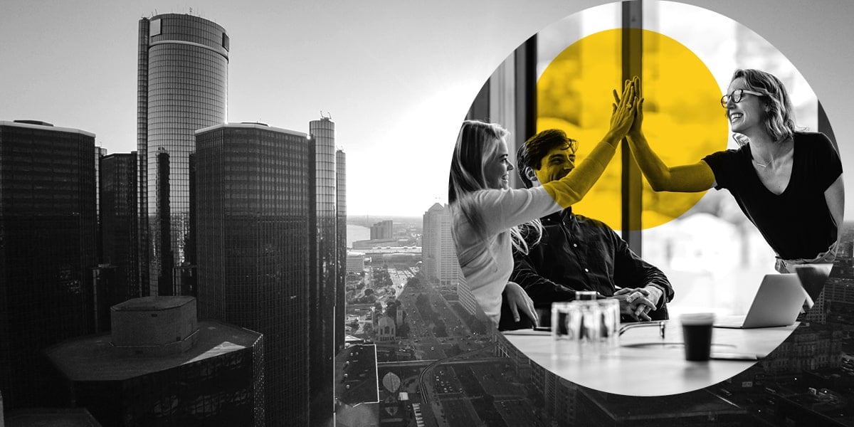 Two business women high-five, superimposed over an image of Detroit's skyline