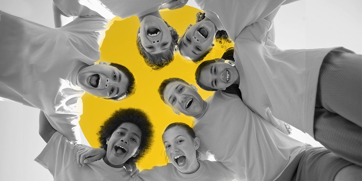 Six summer camp kids with their camp counselor with their heads arranged in a circle